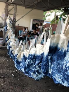 several blue and white bags hanging from a line with people sitting in chairs behind them