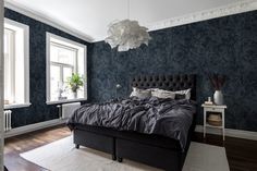 a bedroom with blue wallpaper and black bed in the middle, white rug on the floor