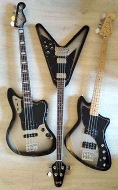 three electric guitars are lined up on the wall together, one is black and the other is white