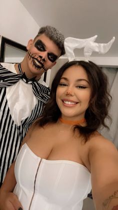 a man and woman in costumes posing for the camera with their faces painted black and white