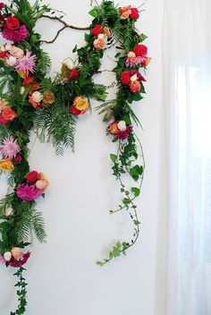 an arrangement of flowers and greenery on a white wall