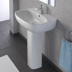 a white sink sitting next to a window in a bathroom with gray tile flooring