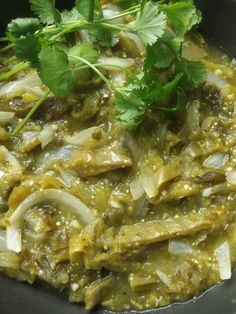 a black bowl filled with green food and garnished with cilantro leaves