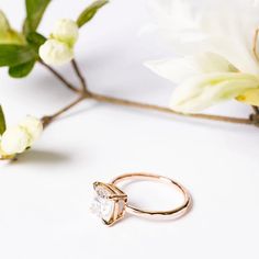 a close up of a ring on a white surface with flowers in the back ground