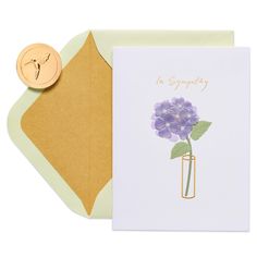 a greeting card with a purple flower in a vase on the front and gold envelope