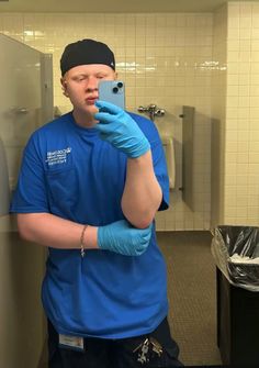 a man in blue shirt taking a selfie with his cell phone and gloves on