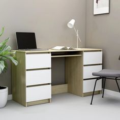 a desk with a laptop on it next to a potted plant and a chair