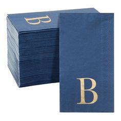 blue paper napkins with gold monogrammed letters and glasses on the top one