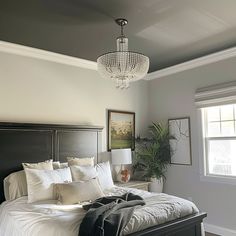 a bedroom with a large bed and chandelier hanging from it's ceiling