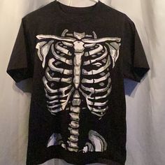 Brand New Black T-Shirt Just In Time For Halloween. Look Stylish Straight From The Graveyard When You Dress Up In This Skeleton Rib Cage T-Shirt. This Black T-Shirt Features A White Skeletal Graphic Printed On The Entire Front Of Shirt. Blank On The Backside. The Perfect Shirt For A Spooky Halloween Night Of Fright! This Soft Comfy Standard Fit Shirt Is Made From 100% Polyester. *Actual Item Purchases Shown In Photo. Color May Vary Due To Camera Flash And Color Variations Of Computer / Phone Scr Skeleton Rib Cage, Halloween Graphic, T Shirt Costumes, Camera Flash, Skeletal, Rib Cage, Halloween Night, Graveyard, Phone Screen