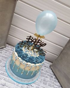 a blue and white cake with balloons on top