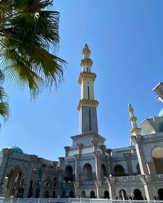 a tall white building with a clock on it's side and a palm tree in the foreground