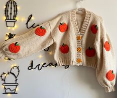 a knitted sweater with pumpkins on it hanging from the wall next to lights