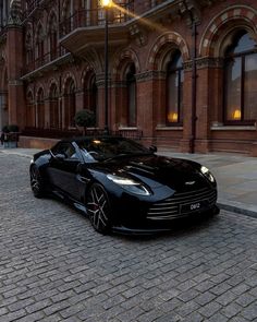 a black sports car parked in front of a brick building on a cobblestone street