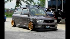 a grey car with yellow rims parked next to other cars