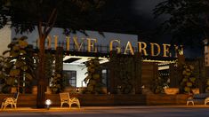 a night time view of a building with lights on it and benches in the foreground