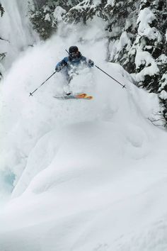 a man riding skis down the side of a snow covered slope next to trees