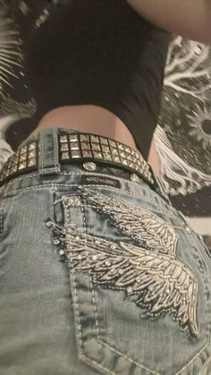 the back of a woman's jeans with an angel design on it and her hand in her pocket