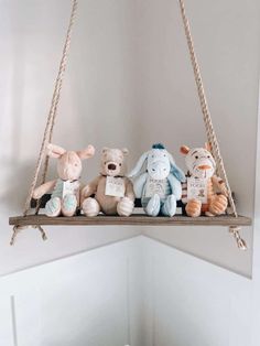 several stuffed animals are sitting on a wooden shelf with rope hanging from the ceiling above them