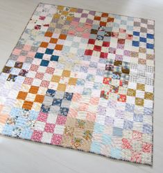 a multicolored patchwork quilt is laying on the floor