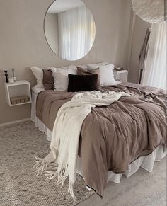 a bedroom with a large bed, mirror and white curtains on the windowsills