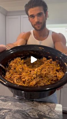 a man holding up a large pot full of food