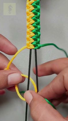 two hands are working together to make a piece of string art with yellow and green yarn