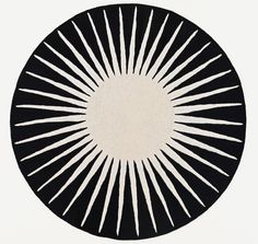 a black and white circular rug with sunbursts on the center, in front of a white background