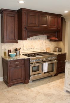 a large kitchen with wooden cabinets and stainless steel stove top oven in the center of the room