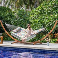 a woman sitting in a hammock next to a pool