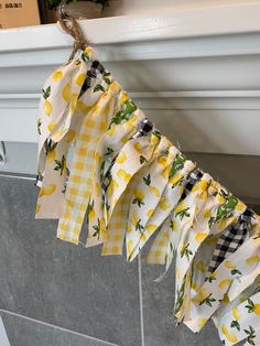 a yellow and white gingham cloth hanging from a window sill with lemons on it