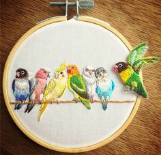 a group of birds sitting on top of a wooden table next to a embroidery hoop