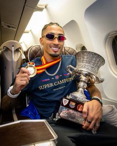 a man sitting on an airplane holding up a trophy