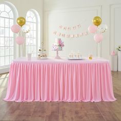 a pink table with balloons and cake on it