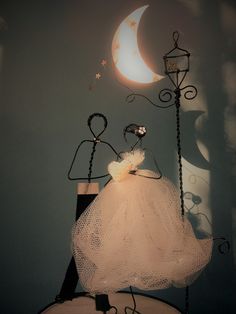 a white dress on top of a wooden table next to a moon and wire sculpture