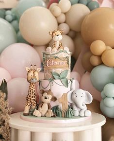 a cake with giraffes and other animals on it in front of balloons