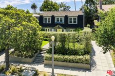 an aerial view of a house with trees and bushes in the foreground, surrounded by greenery