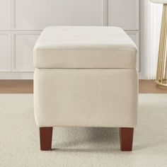 a white foot stool sitting on top of a carpeted floor next to a lamp