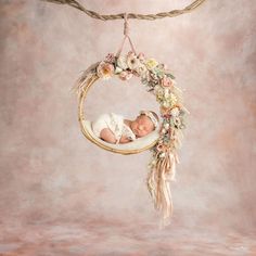 a newborn baby is sleeping in a flowered hammock hanging from a twig