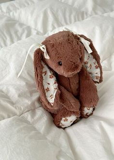 a brown stuffed animal sitting on top of a white bed sheet covered in sheets and pillows