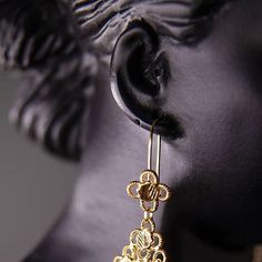 a woman's face wearing gold earrings with filigrees on the ear