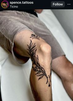 a man laying on top of a bed with tattoos on his arm and leg next to him