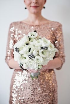 a woman in a sequin dress holding a bouquet of white and black flowers on her wedding day