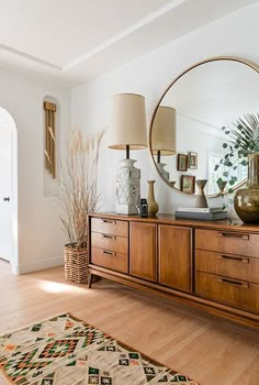 a living room with a large mirror on the wall next to a dresser and lamp