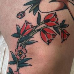 a woman's thigh with flowers and leaves on the side, tattooing it