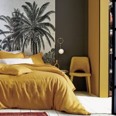 a bedroom with yellow linens and palm trees on the wall