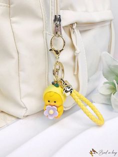 a white purse with a yellow key chain attached to it