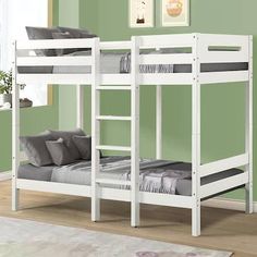 a white bunk bed sitting on top of a hard wood floor next to a green wall