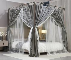 a canopy bed with sheer drapes and curtains on the sides, in a bedroom