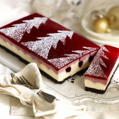 a piece of cheesecake with red and white topping on a plate next to a fork